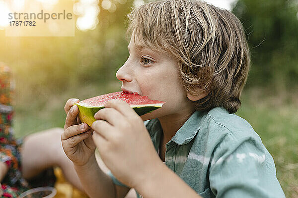 Junge isst Wassermelone im Park