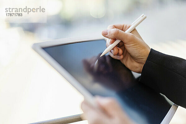 Hand einer Geschäftsfrau  die eine digitalisierte Stiftzeichnung auf einem Tablet-PC hält