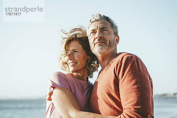 Smiling blond woman with man at beach on sunny day