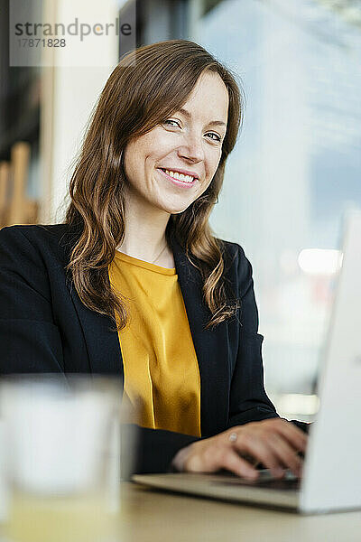 Lächelnde Geschäftsfrau mit Laptop im Café