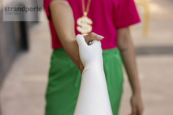 Woman holding hands of mannequin