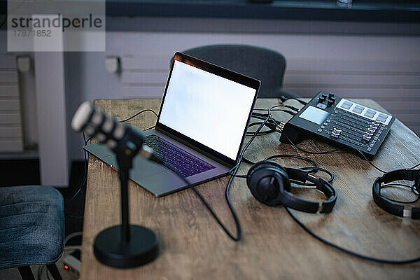 Laptop mit Headset auf dem Schreibtisch im Radiosender