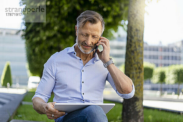Geschäftsmann telefoniert mit digitalem Tablet im Büropark