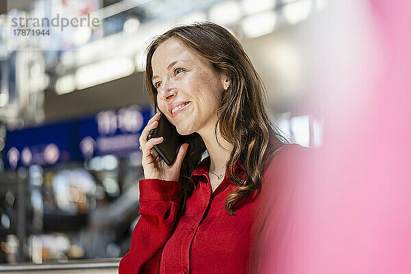 Lächelnde Frau mit braunen Haaren  die mit dem Mobiltelefon spricht