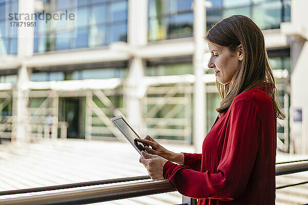 Geschäftsfrau arbeitet am Geländer am Tablet-PC