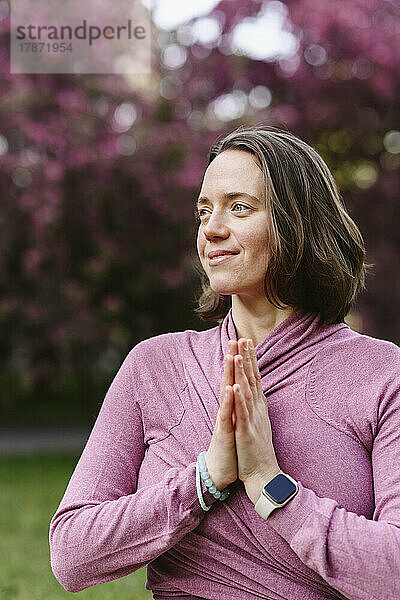Lächelnde Frau mit gefalteten Händen beim Yoga