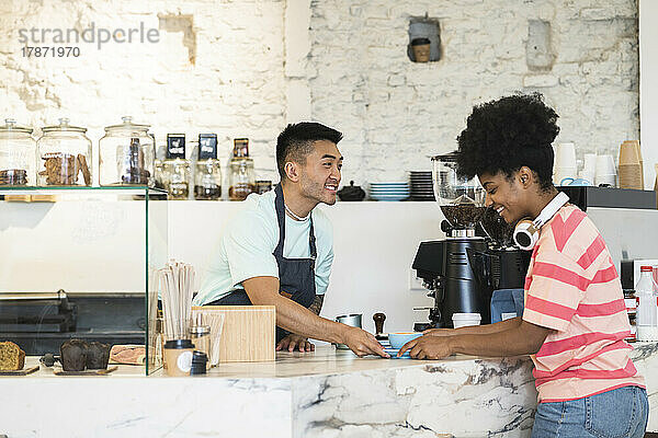 Lächelnder Mann  der dem Kunden im Café Kaffee serviert