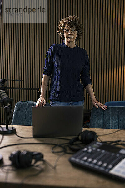 Radio-DJ steht am Schreibtisch im Aufnahmestudio