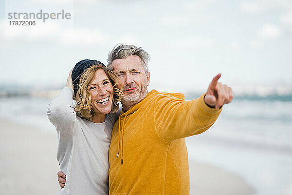 Glückliche Frau und Mann gestikulieren am Strand
