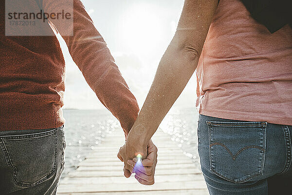 Paar hält Händchen am Strand an einem sonnigen Tag