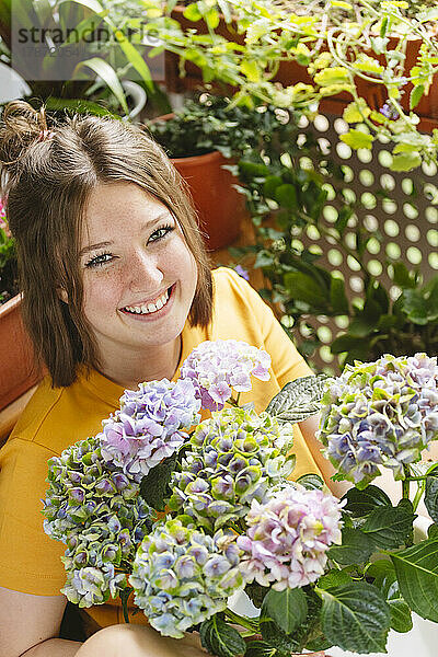 Glückliches Mädchen mit Hortensienblüten auf dem Balkon
