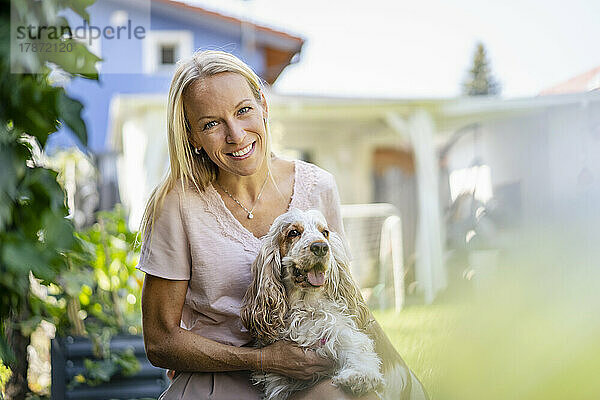 Porträt einer lächelnden Frau mit Hund im Garten