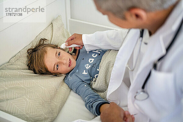 Arzt untersucht Jungen zu Hause im Bett
