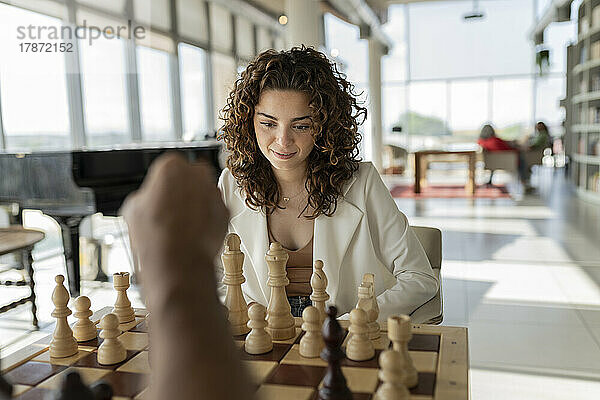 Junge Geschäftsfrau mit lockigem Haar spielt Schach im Büro