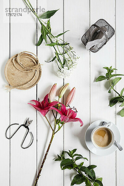 Pair of scissors  cup of coffee and freshly cut flowers lying on wooden surface