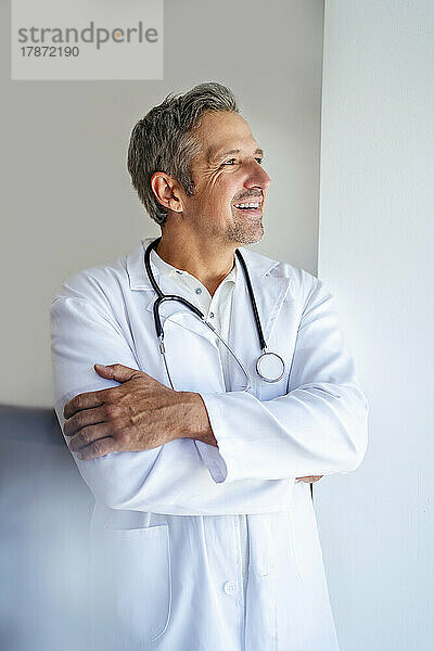 Smiling doctor with arms crossed looking away