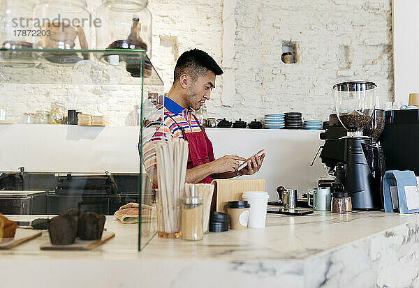 Mann benutzt Smartphone und arbeitet im Café