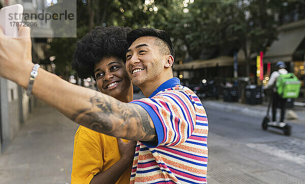Lächelnder junger Mann  der mit einer Frau ein Selfie auf dem Smartphone macht