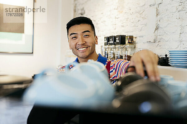 Lächelnder junger Mann  der im Café arbeitet