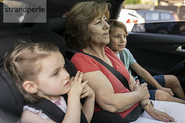 Geschwister sitzen mit Großmutter im Auto
