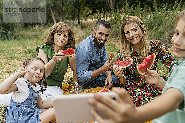 Lächelnder Junge macht Selfie mit Familie im Park