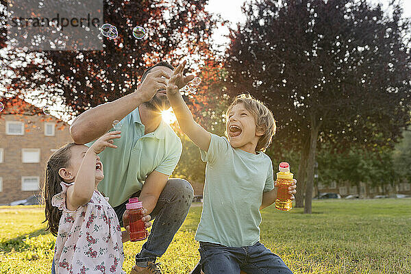 Mann bläst Seifenblasen von Sohn und Tochter im Park