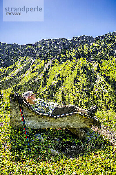 Ältere Frau liegt auf Holzbank  Berg Nebelhorn  Allgäu  Bayern  Deutschland