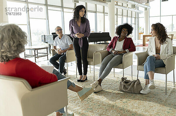 Geschäftsfrau tauscht Ideen mit Kollegen aus  die im Büro sitzen
