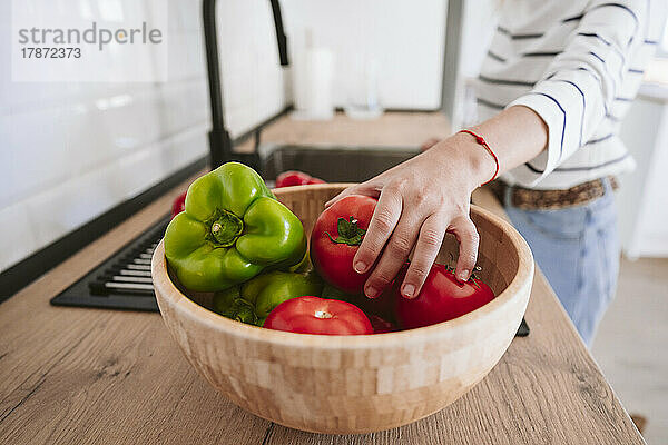 Frau pflückt Tomaten aus Schüssel zum Waschen in der Küche