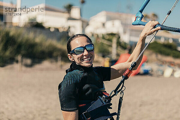 Happy woman kiteboarding at beach on sunny day