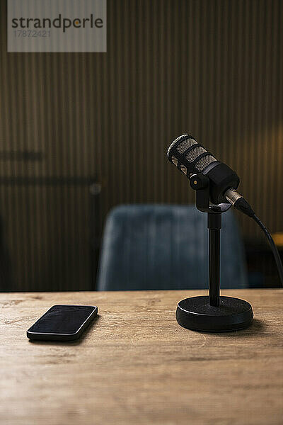 Mobile phone by microphone on desk in recording studio
