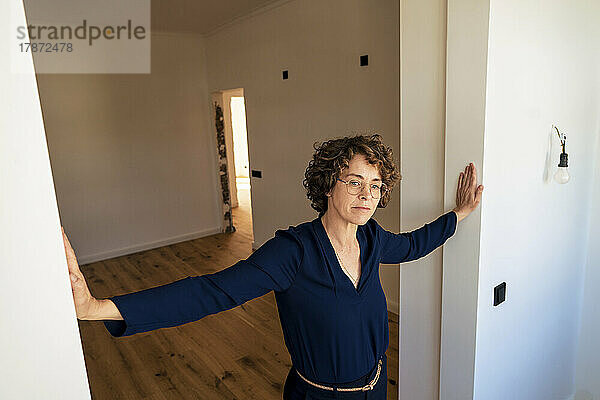 Nachdenkliche Verkäuferin steht vor der Tür eines neuen Zuhauses