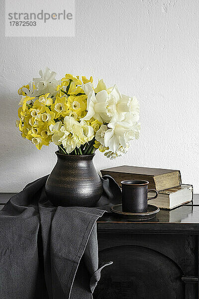 Studio shot of vase with blooming daffodils standing on rustic table