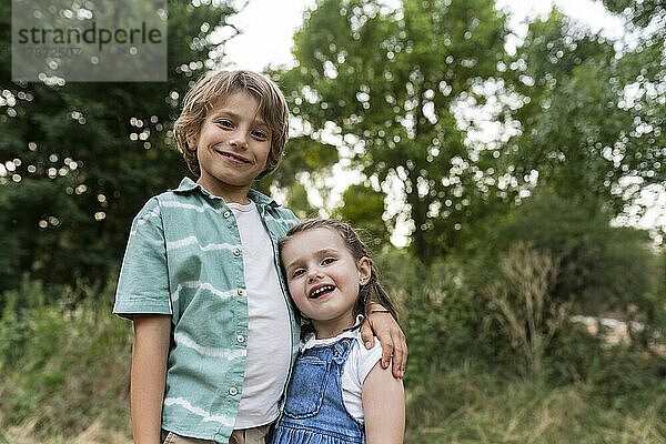 Smiling brother and sister standing at park