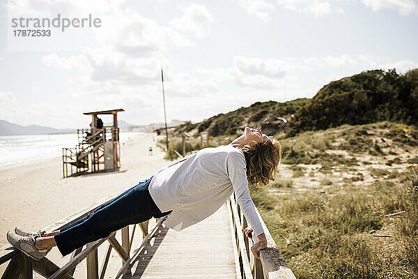 Aktive reife Frau balanciert auf der Promenade am Strand