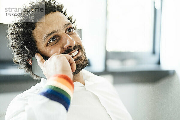 Lächelnder Geschäftsmann  der im Büro mit dem Mobiltelefon spricht