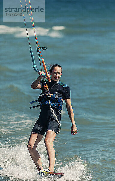 Lächelnde Frau beim Kitesurfen im Meer