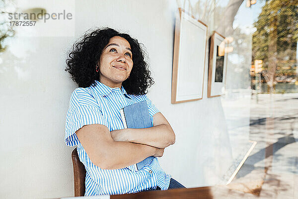 Nachdenkliche Frau mit Tablet-PC lehnt an der Wand im Café