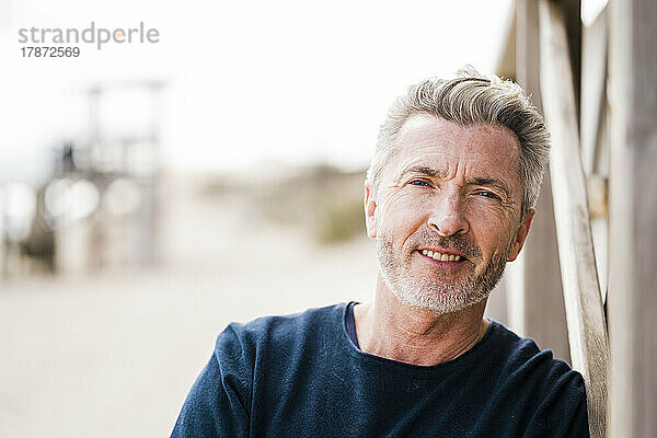 Glücklicher reifer Mann mit grauen Haaren am Strand