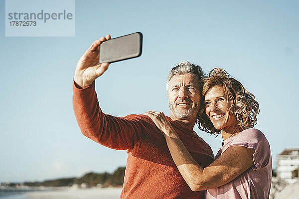 Lächelnder Mann macht Selfie mit Frau per Smartphone