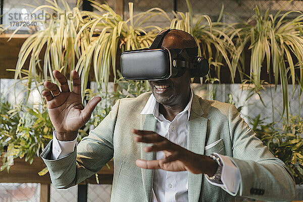 Glücklicher Geschäftsmann mit gestikulierendem Virtual-Reality-Simulator