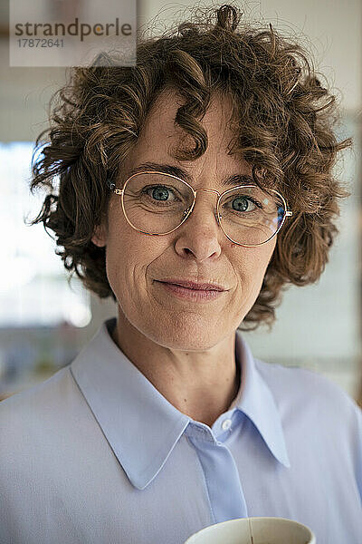 Lächelnde Geschäftsfrau mit braunen Locken und Brille