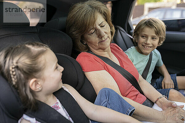Geschwister schauen Großmutter an  die im Auto schläft