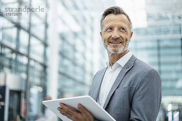 Lächelnder reifer Geschäftsmann mit digitalem Tablet