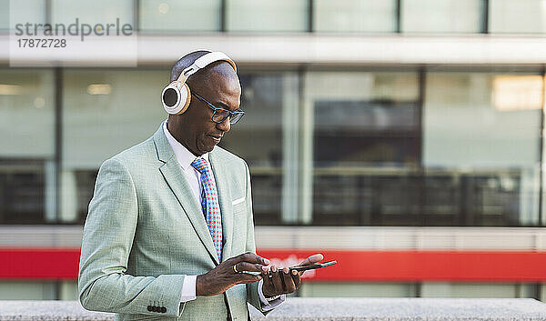 Reifer Geschäftsmann mit kabellosen Kopfhörern und Tablet-PC