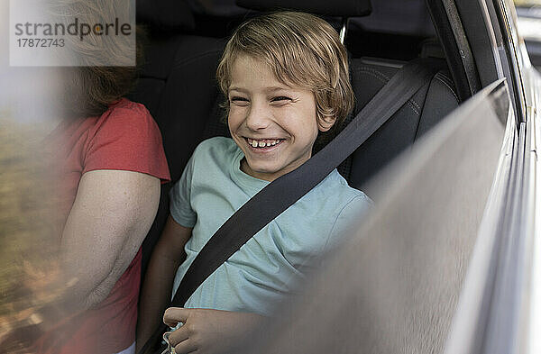 Lächelnder Junge sitzt neben Großmutter im Auto