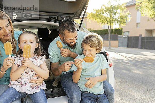Glückliche Familie  die hinten im Auto Eis isst