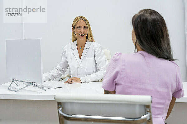 Lächelnder Arzt diskutiert mit Patient in der Klinik