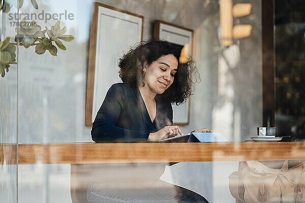 Frau sitzt mit Tablet-PC am Tisch im Café