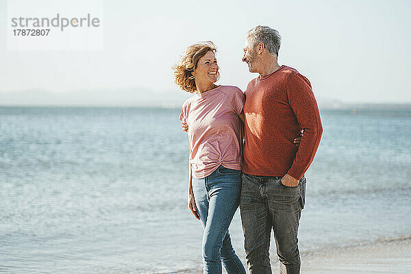 Glückliches Paar  das an einem sonnigen Tag am Strand spaziert